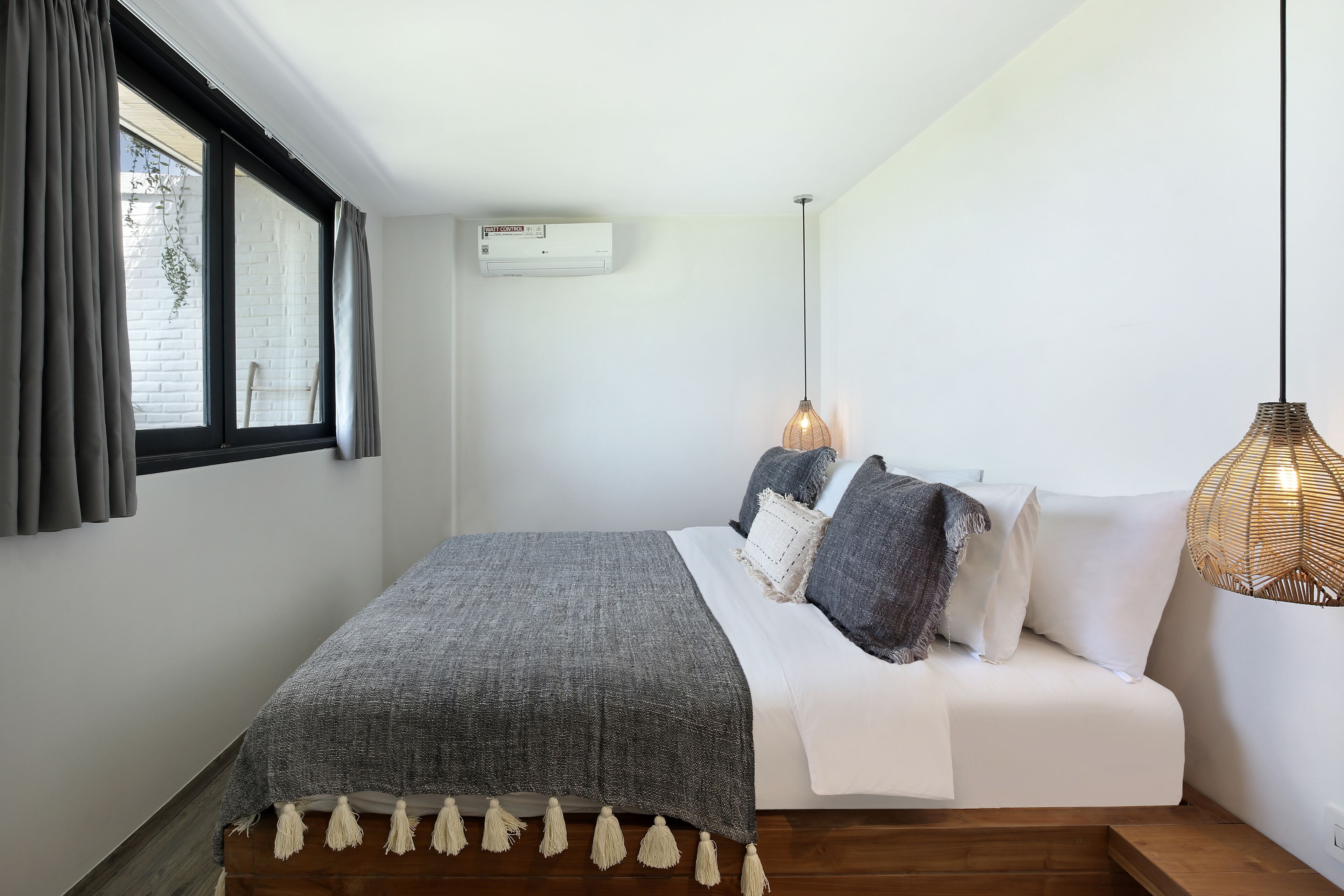 A bedroom with a bed, a hanging light fixture, and a window with curtains.