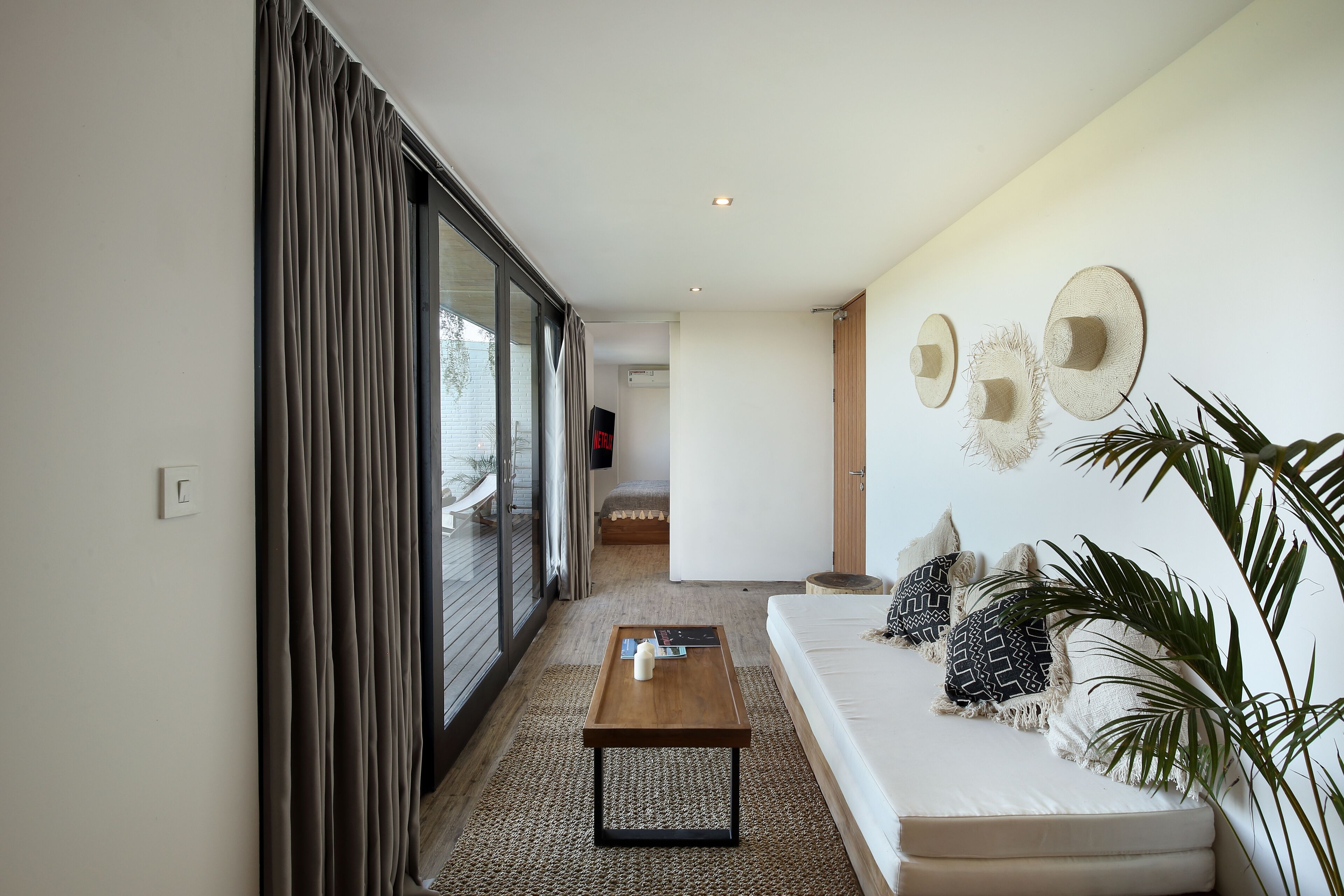 A modern living room with a sofa, a coffee table, and a large window with curtains.