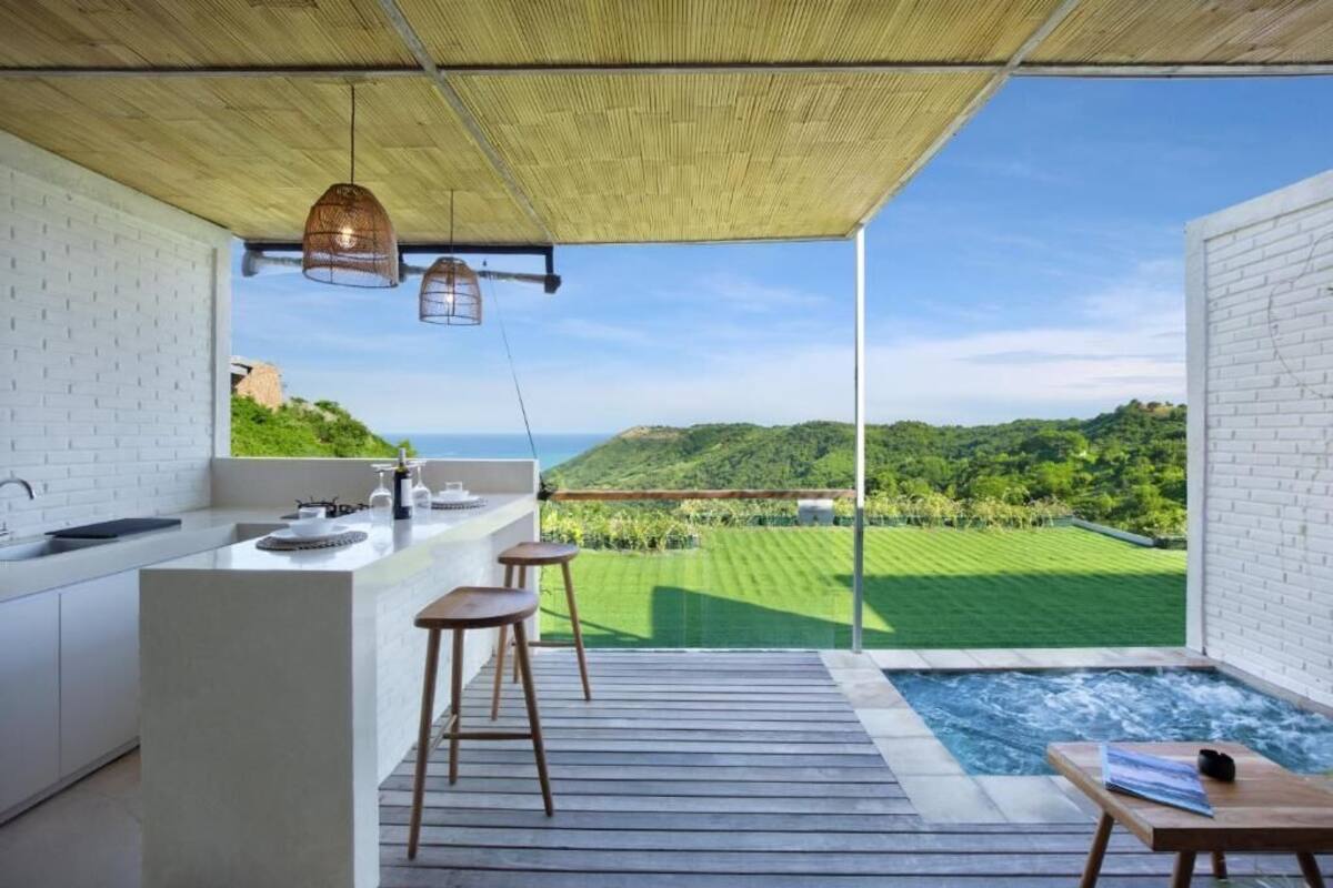 Una cocina moderna con una isla grande, un jacuzzi y vistas a un paisaje verde y exuberante.