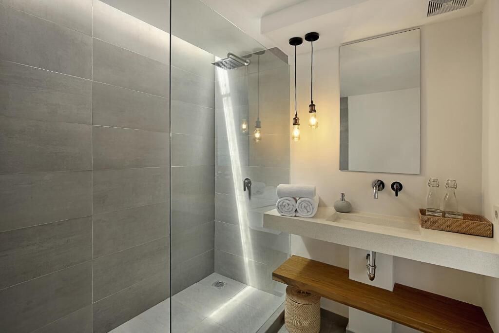 A modern bathroom with a shower, a sink with a mirror, and a wooden vanity.