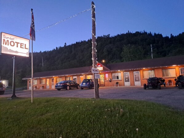A motel with a signboard, a parking area, and a building with a red roof. - Sunset Motel (Schreiber)