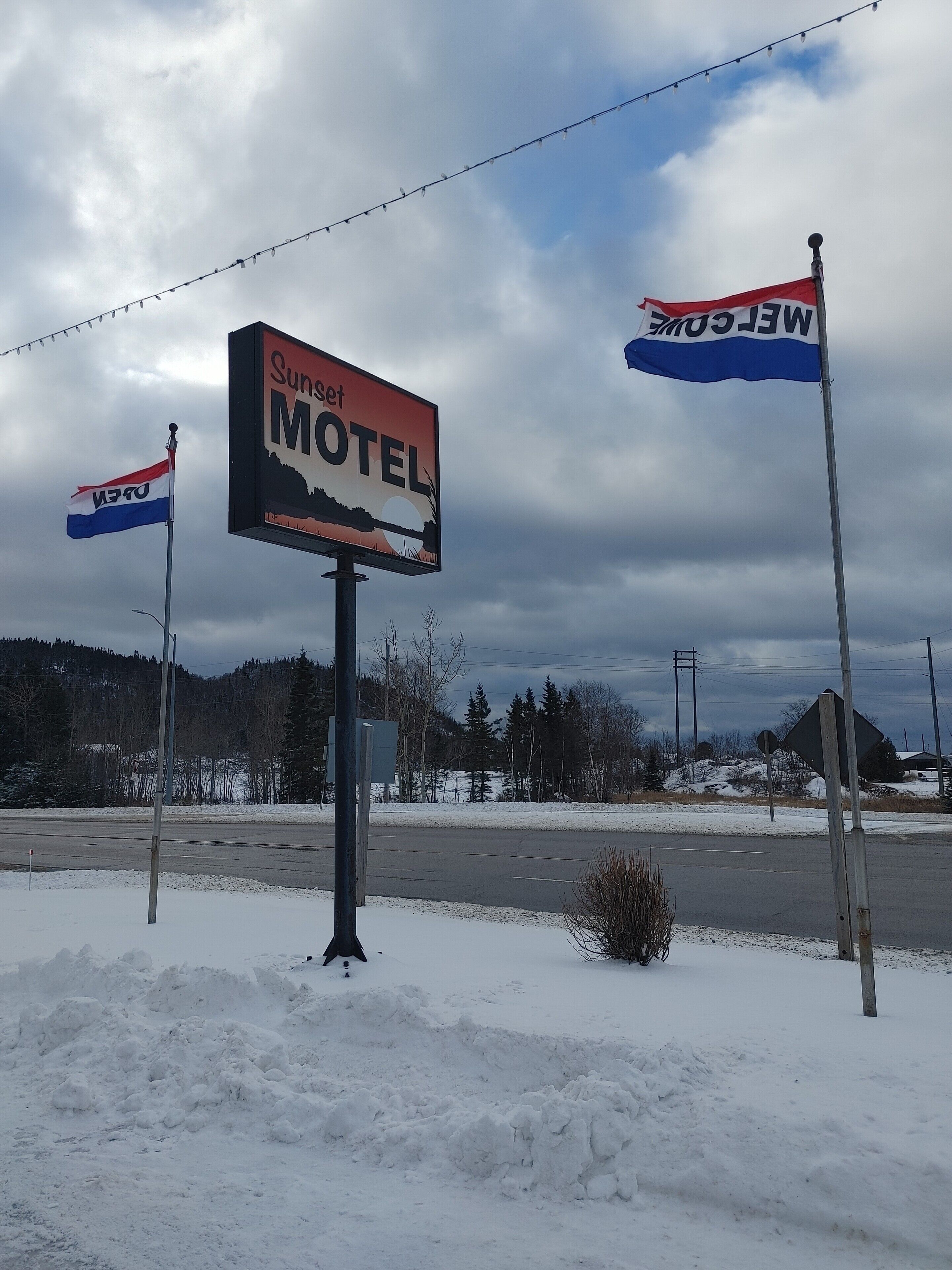 Motel Schild mit Sonnenuntergangsdarstellung, umgeben von Schnee.