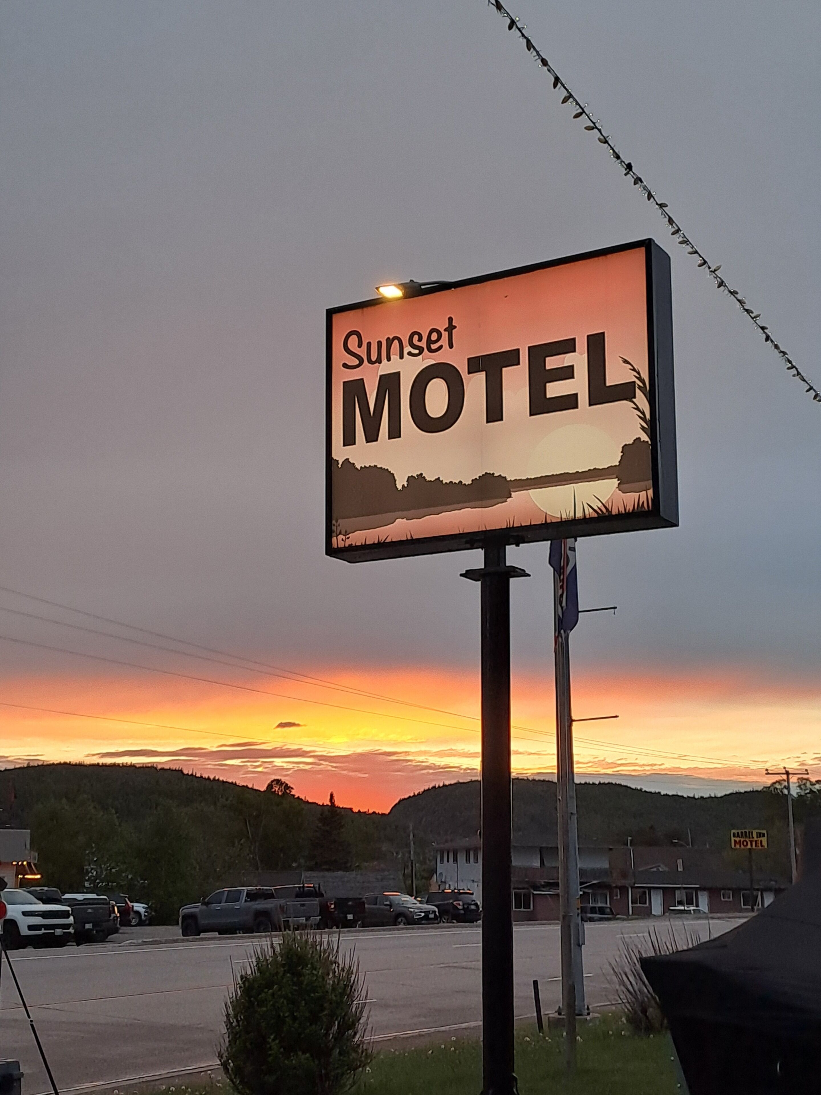 A motel sign with the name 'Sunset Motel' against a sunset sky.