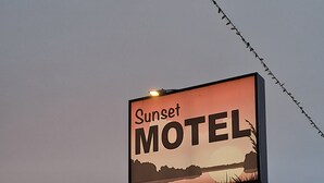 A motel sign with the name 'Sunset Motel' against a sunset sky.