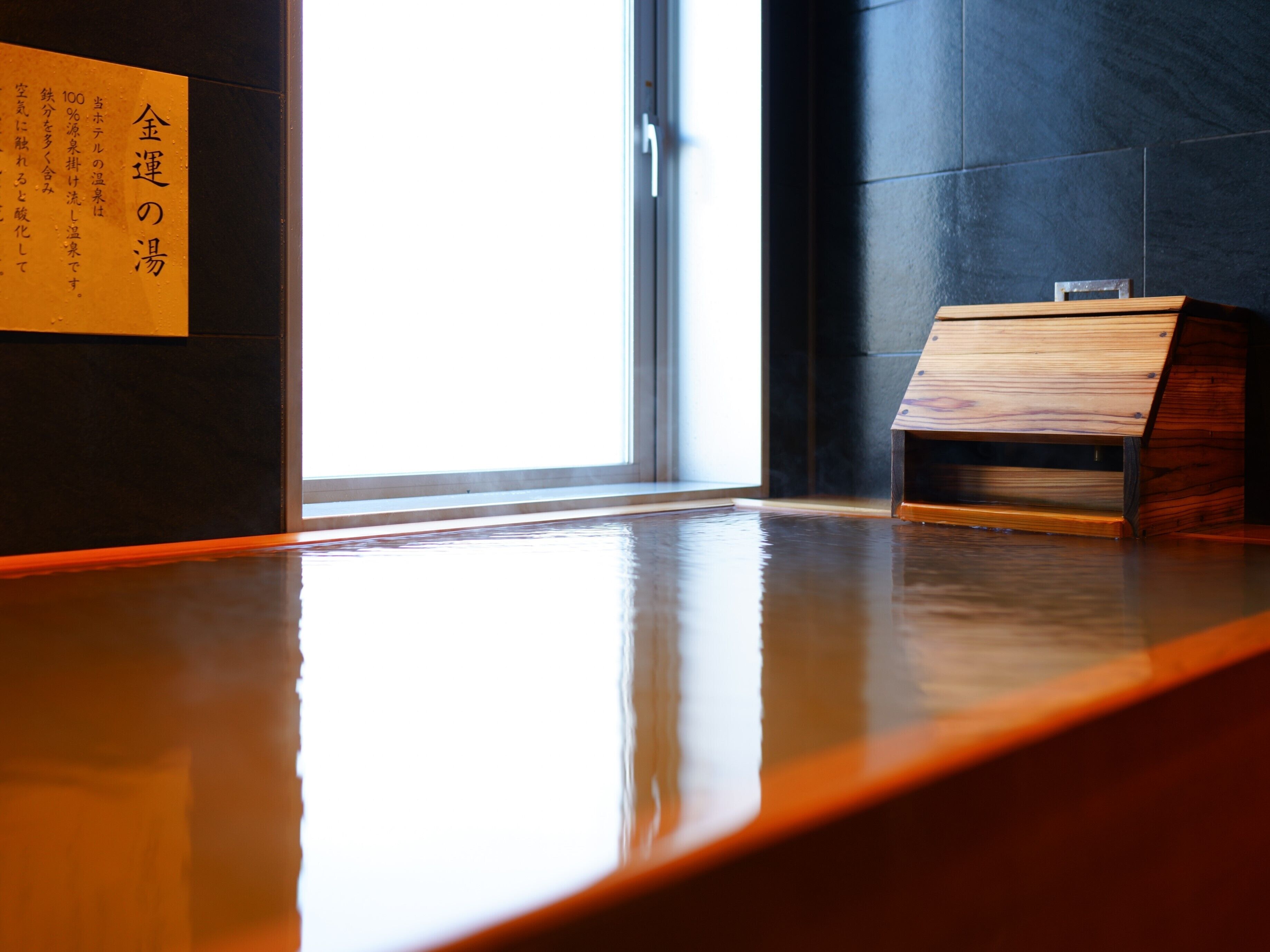 A wooden reception desk in a modern interior with a large window and a sign on the wall.