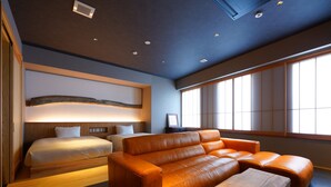 A modern hotel room with a large bed, a sofa, and a wooden coffee table. - MURE Beppu (Beppu)
