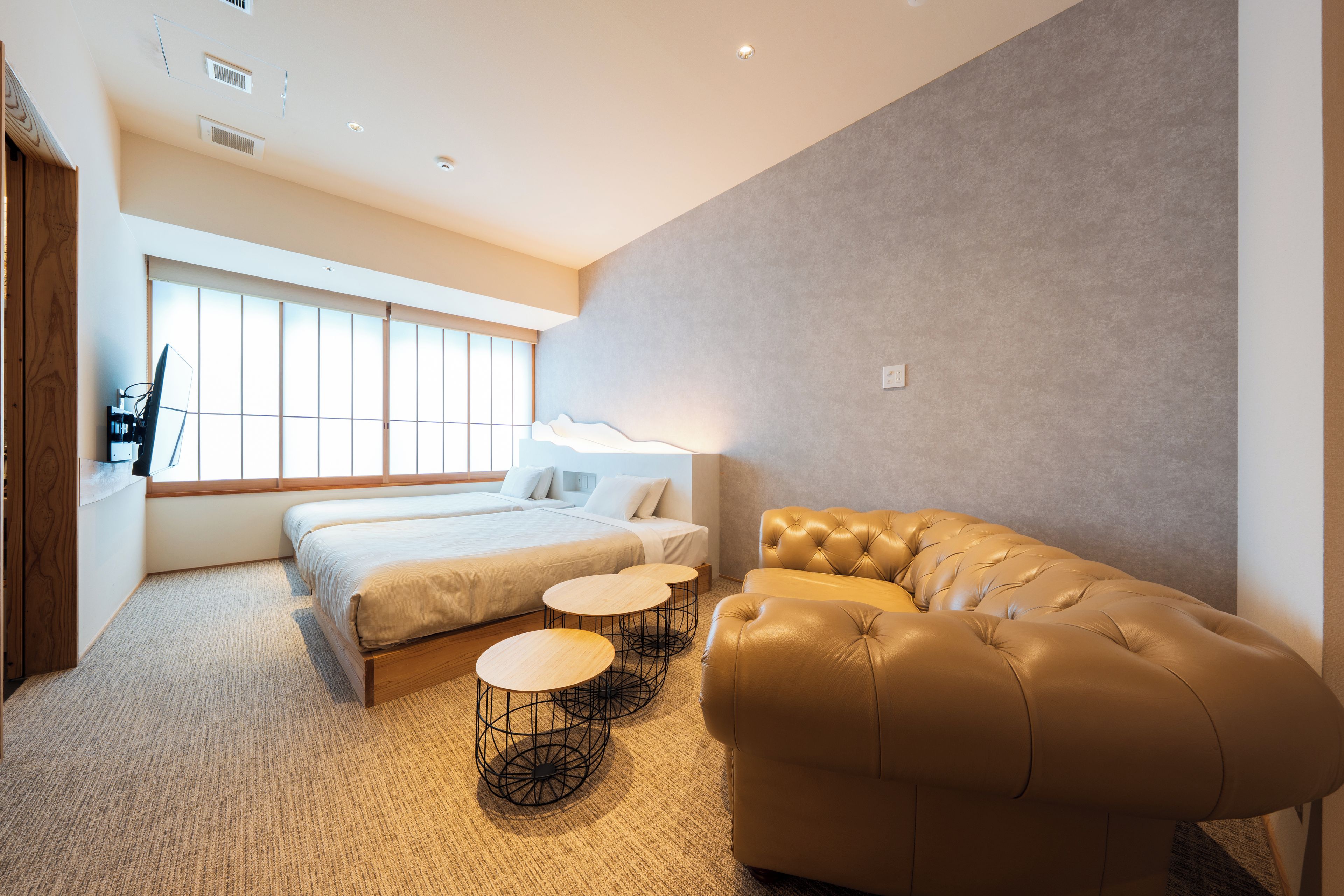 A modern hotel room with a large bed, a sofa, and two small tables.