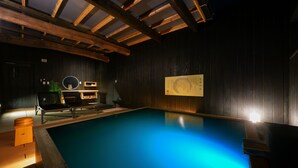 A swimming pool with wooden beams, a lounge area, and a wall with a sign. - MURE Beppu (Beppu)