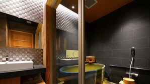 A modern bathroom with a wooden vanity, a large bathtub, and a small wooden stool. - MURE Beppu (Beppu)