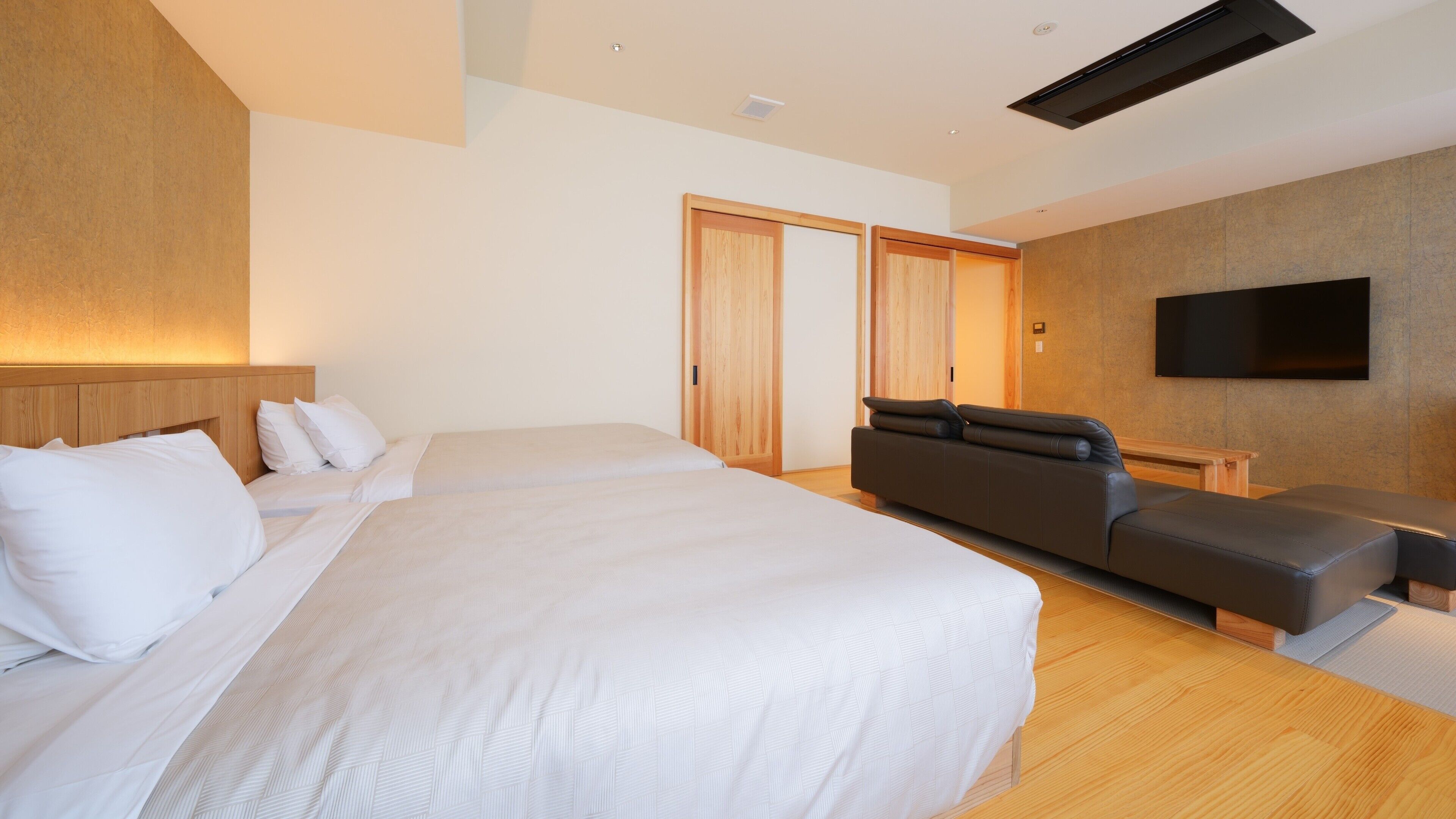 Ett modernt hotellrum med en stor säng, en soffa, en TV och ett trägolv.