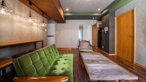 Um interior moderno com um banco estofado em verde, mesas de madeira e iluminação pendente.