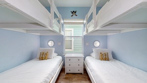 Una habitación con literas, una ventana pequeña y un reloj de pared.