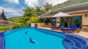 Une piscine dont le bord est revêtu de carrelage, entourée de chaises longues et d’un espace de repos abrité.