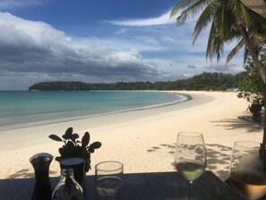 A beach view with a table set for dining, featuring a glass of wine and a bottle. - Luxury Villa with private chef, full staff, wonderful views (Tambon Karon)