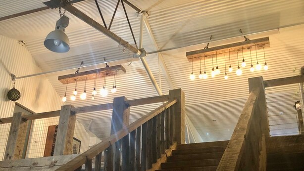 Un escalier en bois avec une rampe en métal, un ventilateur de plafond et des luminaires suspendus.