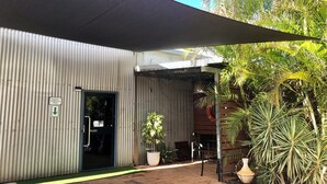 Un bâtiment à l’extérieur recouvert de tôle ondulée, avec un panneau indiquant les places de stationnement réservées aux visiteurs et une porte à pousser.