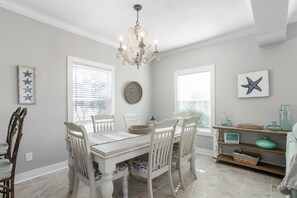 A dining area with a white table and chairs, a chandelier, and decorative items on the walls.