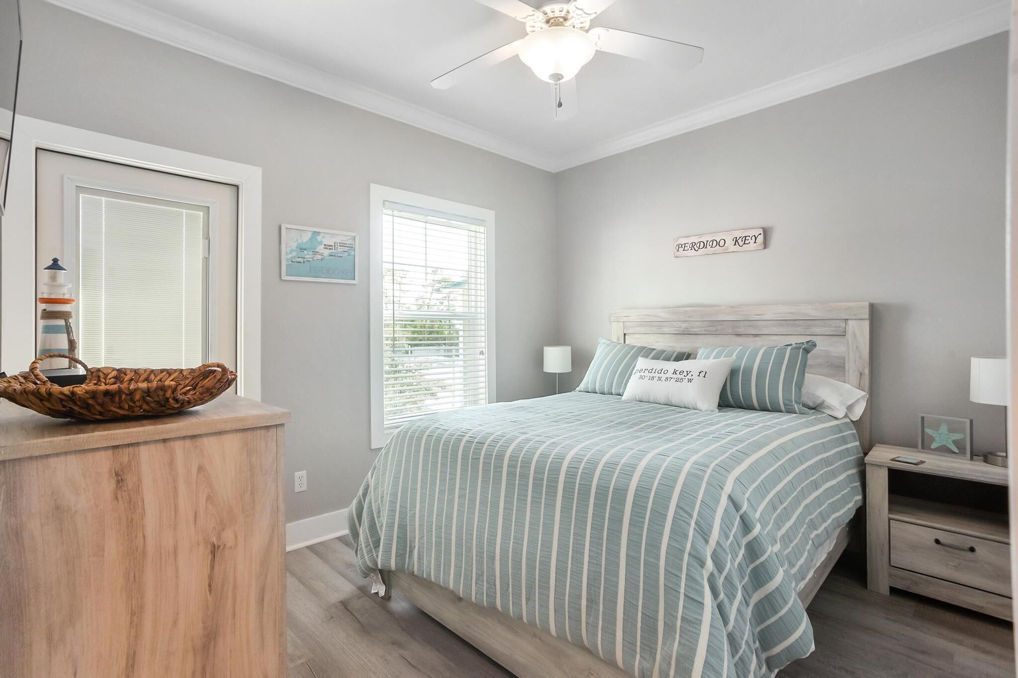 A bedroom with a bed, a nightstand, a wall-mounted shelf, a window with blinds, and a ceiling fan.