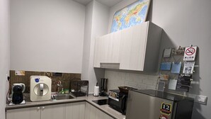 A modern kitchen with white cabinets, a stainless steel refrigerator, a microwave, and a coffee maker.