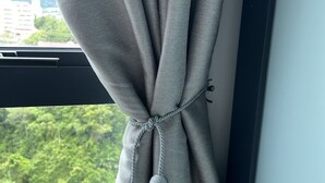 A window with a curtain tied at the top, featuring a knot and two pom-poms.