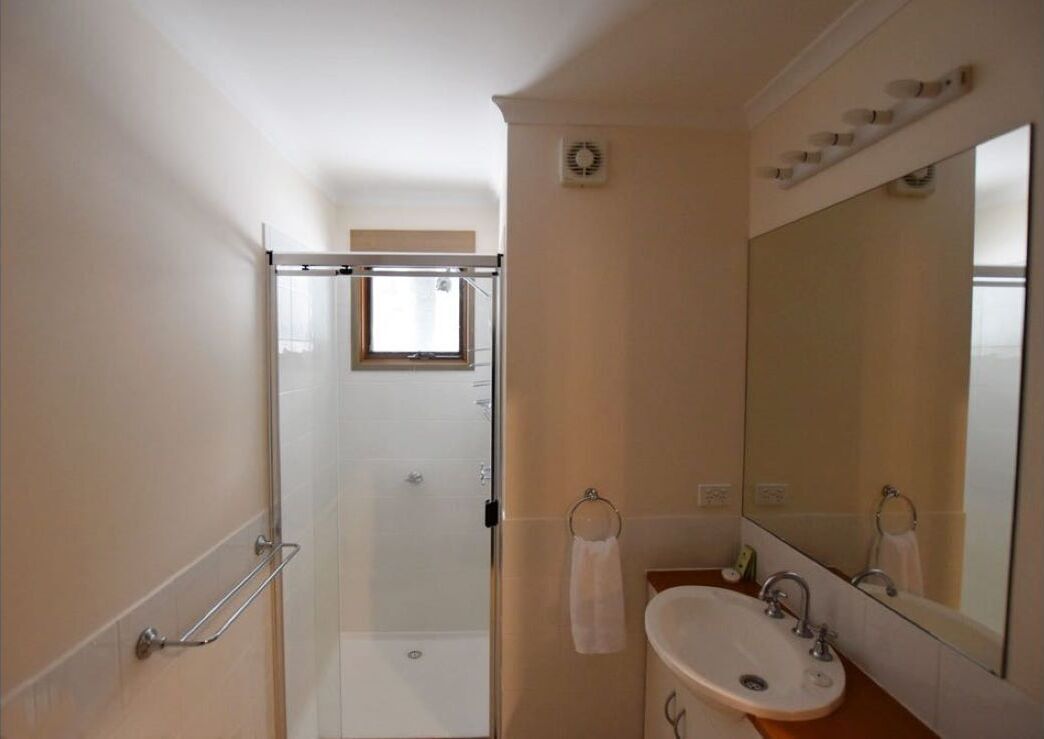 Une salle de bain avec une douche à parois de verre, un lavabo avec un miroir et un porte-serviettes.