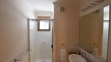 Une salle de bain avec une douche à parois de verre, un lavabo avec un miroir et un porte-serviettes.