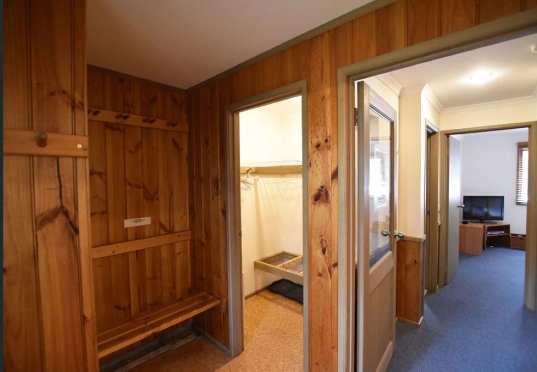 A room with wooden paneling, a bed, a desk, and a television.