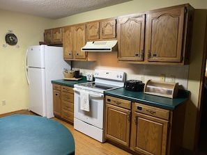 A kitchen with wooden cabinets, a white refrigerator, a stove, and a toaster.