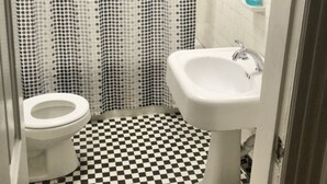 A bathroom with a toilet, a sink, and a shower curtain. - Cantrell’s on Broadway #1 (Nashville)