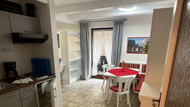 A modern kitchen with a dining area featuring a hexagonal tile floor and a table with red cushions. - Spacious apartment 3 with balcony (Berchtesgaden)