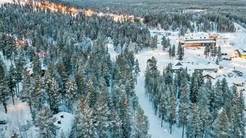 A snow-covered forest with a lodge and a ski lift in the background.