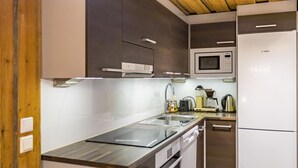 Una cocina moderna con un lavamanos de acero inoxidable, un refrigerador Bosch y un microondas.