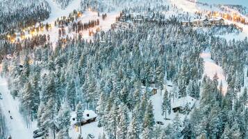 A snow-covered mountain resort with multiple buildings, ski slopes, and a dense forest.