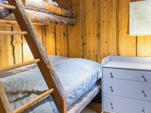 Een houten kamer met stapelbedden, een dressoir en een kaart aan de muur.