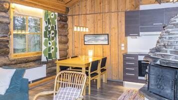 L’intérieur d’une cabane en rondins, avec une table à manger en bois, des chaises, un canapé, une cheminée et un coin cuisine.