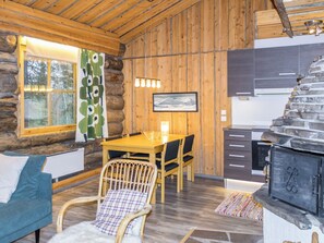 L’intérieur d’une cabane en rondins, avec une table à manger en bois, des chaises, un canapé, une cheminée et un coin cuisine.