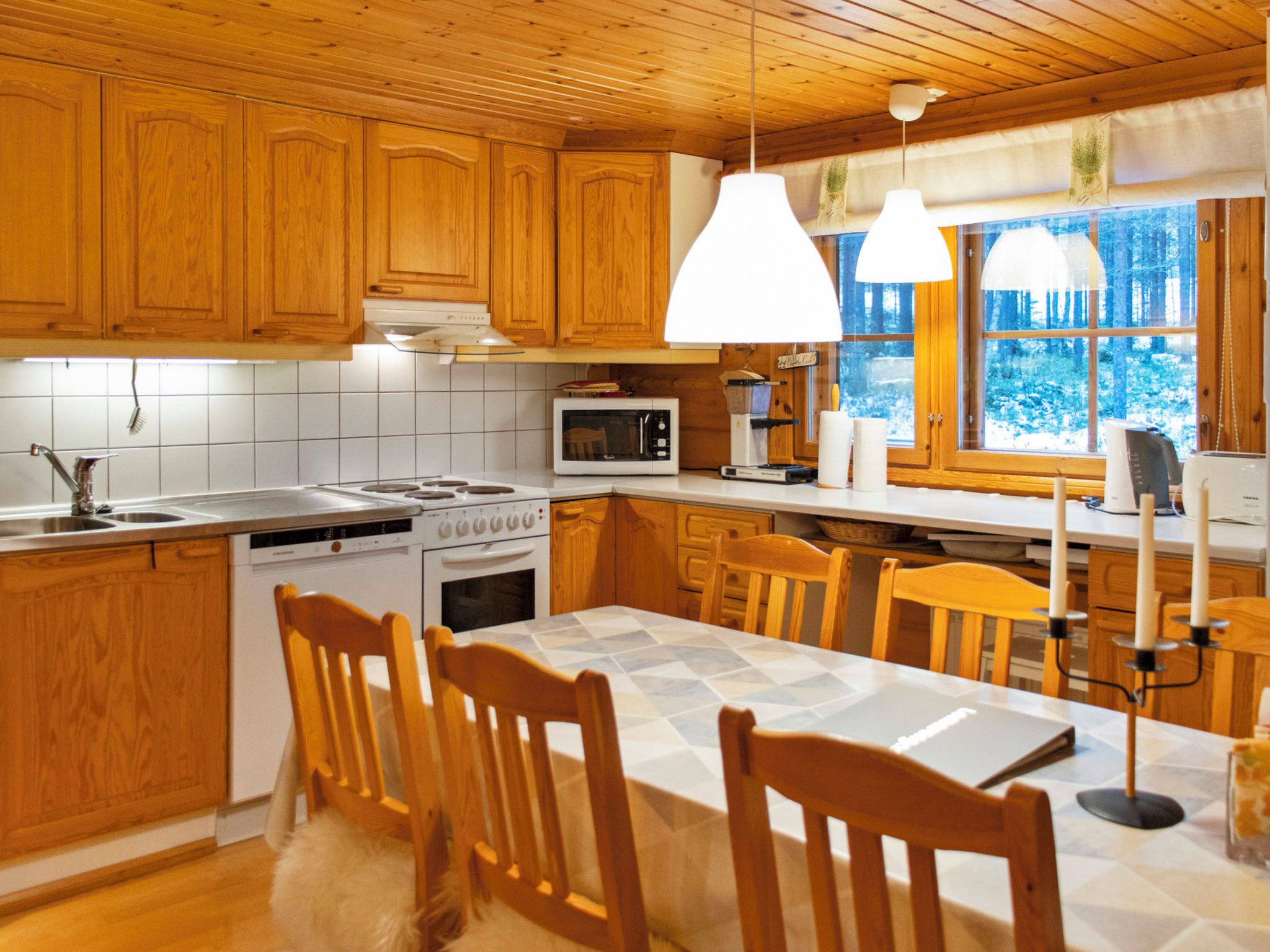 A kitchen with wooden cabinets, a stove, a microwave, and a dining area with chairs and a table.