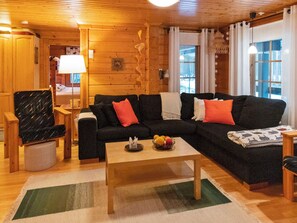 Una sala acogedora con un sofá modular, una mesa de centro de madera y un sillón estampado.