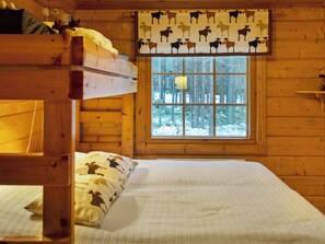 A cabin room with a bunk bed, a window with a view of a snowy forest, and a patterned curtain. - Kuusenkolo by Interhome (Pelkosenniemi)