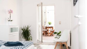 Un dormitorio con cama, escritorio, silla y planta en maceta.