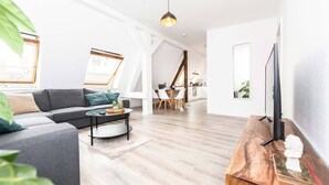 Una sala moderna con un sofá gris, una mesa de centro redonda y una mesita de noche de madera con una escultura.