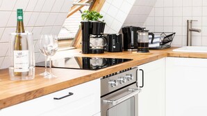 Una cocina moderna con encimera de madera, cafetera, tostadora, hervidor y una botella de vino.