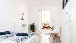 Un dormitorio moderno con cama, mesita de noche y vista a un comedor a través de una puerta abierta.