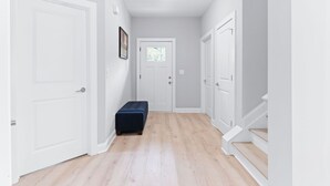 A hallway with white doors, a dark blue bench, and a light wooden floor.
