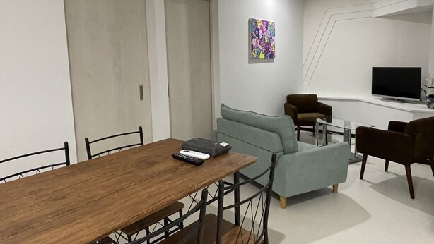 Una sala de estar moderna con una mesa de comedor de madera, un sofá y un televisor.