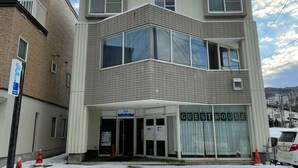 Un edificio de dos pisos con un letrero que dice 'Guesthouse', que presenta un diseño moderno con ventanas amplias y un techo plano.