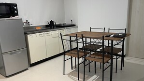 Cocina compacta con refrigerador, microondas, estufa y pileta. Hay una mesa de comedor con sillas.