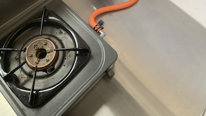 Una estufa a gas con un quemador visible y una tubería de gas con un tubo naranja.