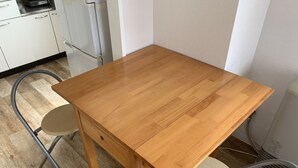 A wooden dining table with two chairs, a kitchen area with white cabinets, and a water heater. - Zenibako House 3F-RoomB (Otaru)