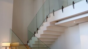Een modern interieur met een glazen balustrade, een stoel en een lamp.